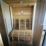 Innere Ansicht einer Holzsauna mit Sitzbank und Bedienfeld an der Wand.