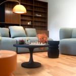 Ein Wohnzimmer mit grauen Sofas, einem runden Tisch und einem Bücherregal.