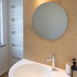 Waschbecken mit Spiegel und Duschbereich im Badezimmer.
