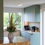 Küche mit grünen Schränken, Fenster und Blumenvase auf Holzoberfläche