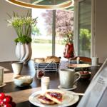 Frühstückstisch mit Kaffee, Obst und Zeitung vor Fenster