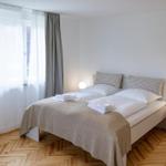 Schlafzimmer mit Doppelbett, Holzboden und Fenster mit Vorhängen.