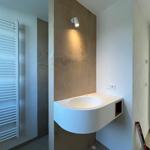 Badezimmer mit Waschbecken, Wandheizung und Beleuchtung.