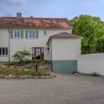 Ein zweistöckiges Haus mit rotem Dach, grünen Fensterläden und einem Kiesweg.