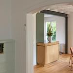 Eingangsbereich mit Holzschrank und Blick in Esszimmer mit Tisch und Stühlen.