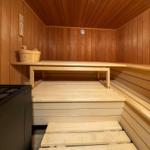Sauna mit Holzbank und Steintisch. Holzwände und -boden. Holzschale auf der Bank.
