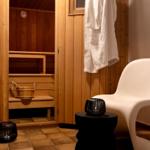 Sauna mit Holzwand, Sitzbank, Eimer und Bademantel an der Tür.