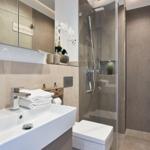 Badezimmer mit Dusche, Waschbecken und Toilette. Moderne Einrichtung mit Spiegel und Blumen.