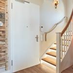 Eingangsbereich mit Holzwand, Tür und Treppe mit Seilgeländer.