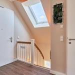 Eingangsbereich mit Treppe, Dachfenster und Tür. Wandbild und Holzboden sichtbar.