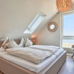 Schlafzimmer mit Dachschrägen, Dachfenster und großem Fenster mit Meerblick.