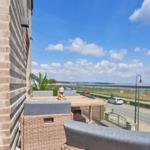 Terrasse mit Sitzgelegenheiten und Blick auf Straße und Wasser.