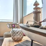 Tisch mit Segelboot und Laterne vor Fenster mit Meerblick
