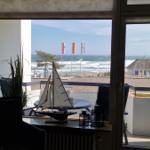 Blick vom Balkon auf das Meer mit Wellen und Flaggen. Modellboot auf Tisch.