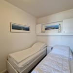 Zimmer mit zwei Betten, Wandbild und Schrank mit Dekoration.