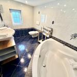 Badezimmer mit Badewanne, Waschbecken und Toilette. Fliesenboden und Wandfliesen.