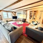 Wohnzimmer mit zwei Sofas, rotem Teppich und Holzbalken an der Decke.