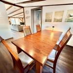 Essbereich mit Holztisch und Stühlen. Im Hintergrund Wohnzimmer mit Sofa.