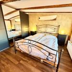 Schlafzimmer mit Doppelbett, Holzboden und Deckenbalken. Zwei Nachttische mit Lampen.
