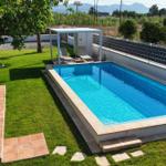 Pool mit Sonnenschutz, Liegen und Grünfläche. Berglandschaft im Hintergrund.