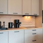 Küche mit Holzrückwand, schwarzen Armaturen und integriertem Backofen.