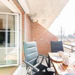 Terrasse mit Tisch, zwei Stühlen und Blumenarrangement. Blick auf Außenbereich.