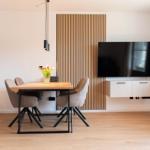 Essbereich mit Tisch, Stühlen und Fernseher an der Wand.