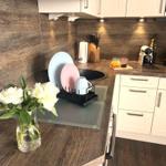 Kitchen with wood finish, sink, dishes, and flowers on the countertop.