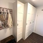 Hallway with white wardrobes, wall decor, and wooden bench