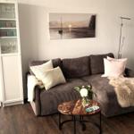 A living room with a brown sofa, decorative cushions, and a round table.