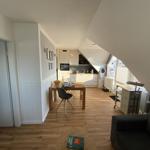 Wohnung mit Essbereich, Küche und Sofa unter Dachschrägen.