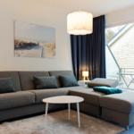 Ein Wohnzimmer mit grauem Sofa, weißem Tisch und Wandbild.