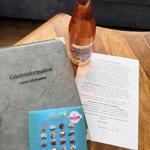 Gästebegrüßung mit Wein, Schokolade und Informationsbroschüre auf Holztisch