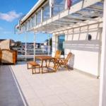 Terrasse mit Tisch, Stühlen und Liegestuhl. Blick auf Stadt und Himmel.