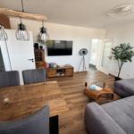 Wohn- und Essbereich mit Holzboden, Sofa, Esstisch und Fernseher.