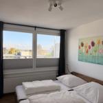Zimmer mit Doppelbett, Fenster und Wandbild.
