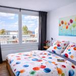 Schlafzimmer mit Bett, Fenster und Wandbild.