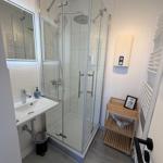 Badezimmer mit Dusche, Waschbecken und Handtuchwärmer.