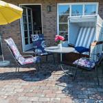 Terrasse mit gelbem Sonnenschirm, Gartenstühlen und Tisch vor Backsteinhaus.