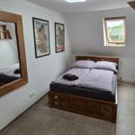 Bedroom with wooden bed, mirror, and window. Walls decorated with pictures.