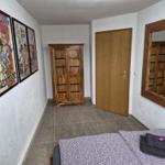 Bedroom with bed, wooden wardrobe, mirror, and wall posters.