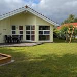 House with terrace, playground, and sandbox on green lawn.