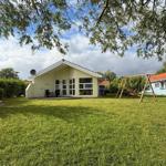 A yellow vacation house with terrace and playground in the grass. A boat is standing up.