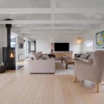 Wohnzimmer mit Kamin, Sofa und Fernseher. Holzboden und weiße Wände.