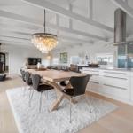 Eingangsbereich mit Essbereich, Küche und Wohnzimmer. Holzfußboden, weißer Teppich und Esstisch mit Stühlen.