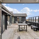 Terrasse mit Tisch, Bänken und Sitzgelegenheiten. Blick auf Haus und Himmel.