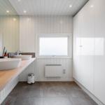 Badezimmer mit zwei Waschbecken, Holzunterlage und großen weißen Schränken.