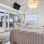 Schlafzimmer mit Bett, Glasfront und Wandbild. Decke mit Lampe und TV.
