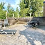 Deck with lounge chairs and table set, surrounded by wooden railing and trees.