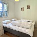 Bedroom with bed, window, and dresser. Wall pictures and wooden floor.